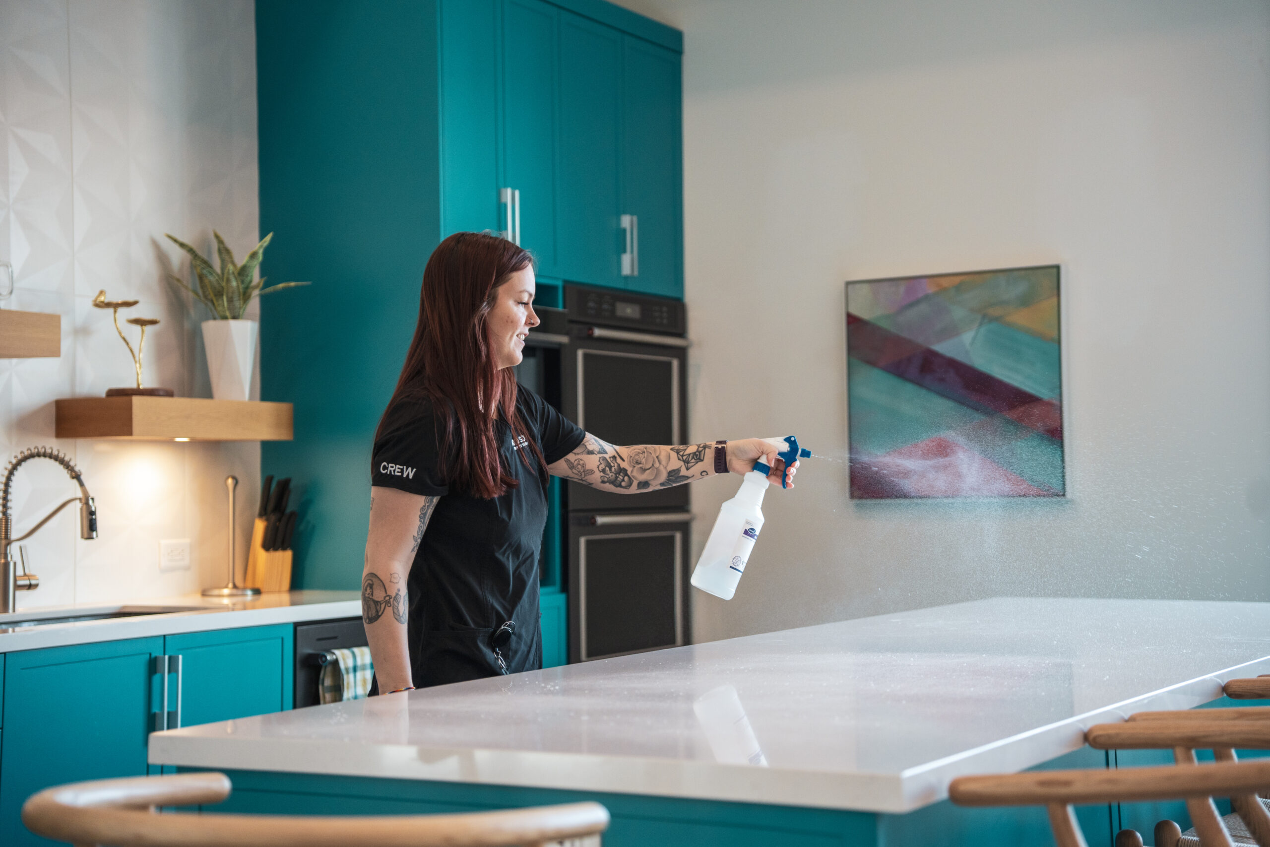 Good Sorts cleaning crew member spraying cleaning product on countertop.