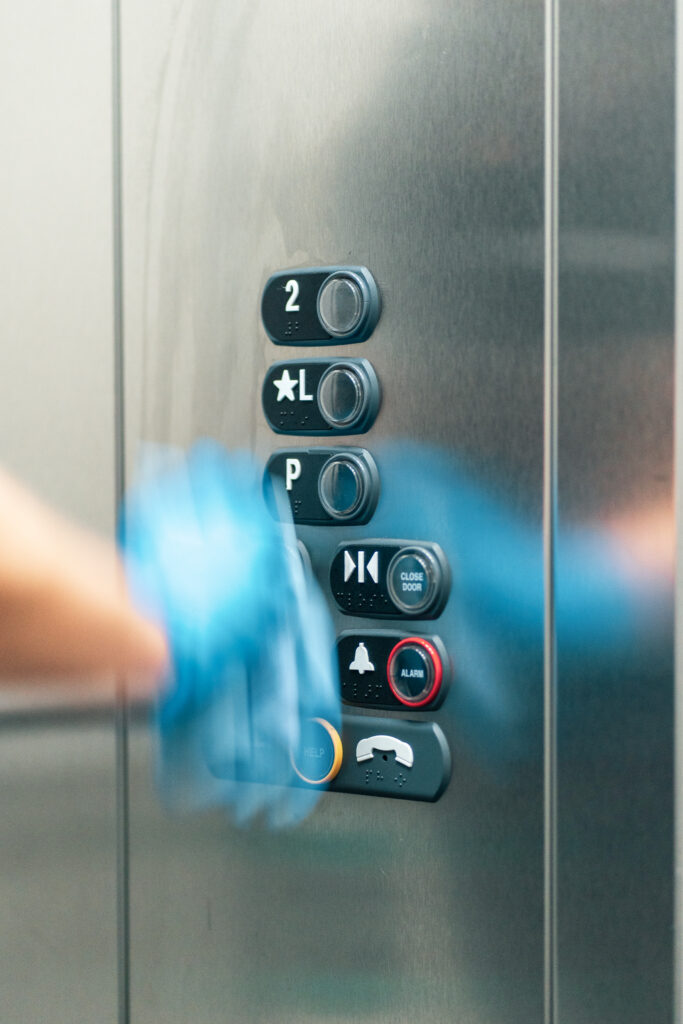 Good Sorts team member wearing blue glove wiping down elevator buttons