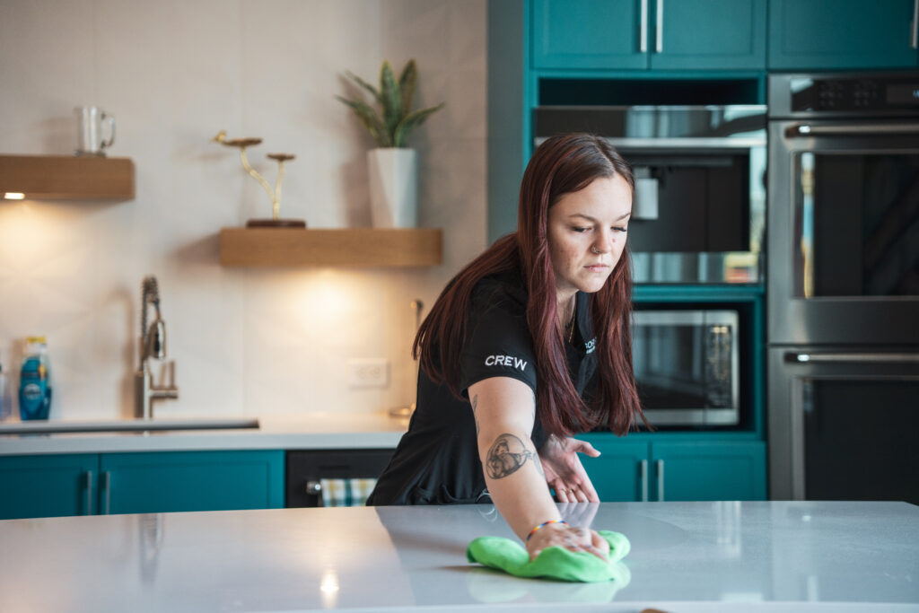 Good Sorts crew member wiping down countertop with green rag in kitchen