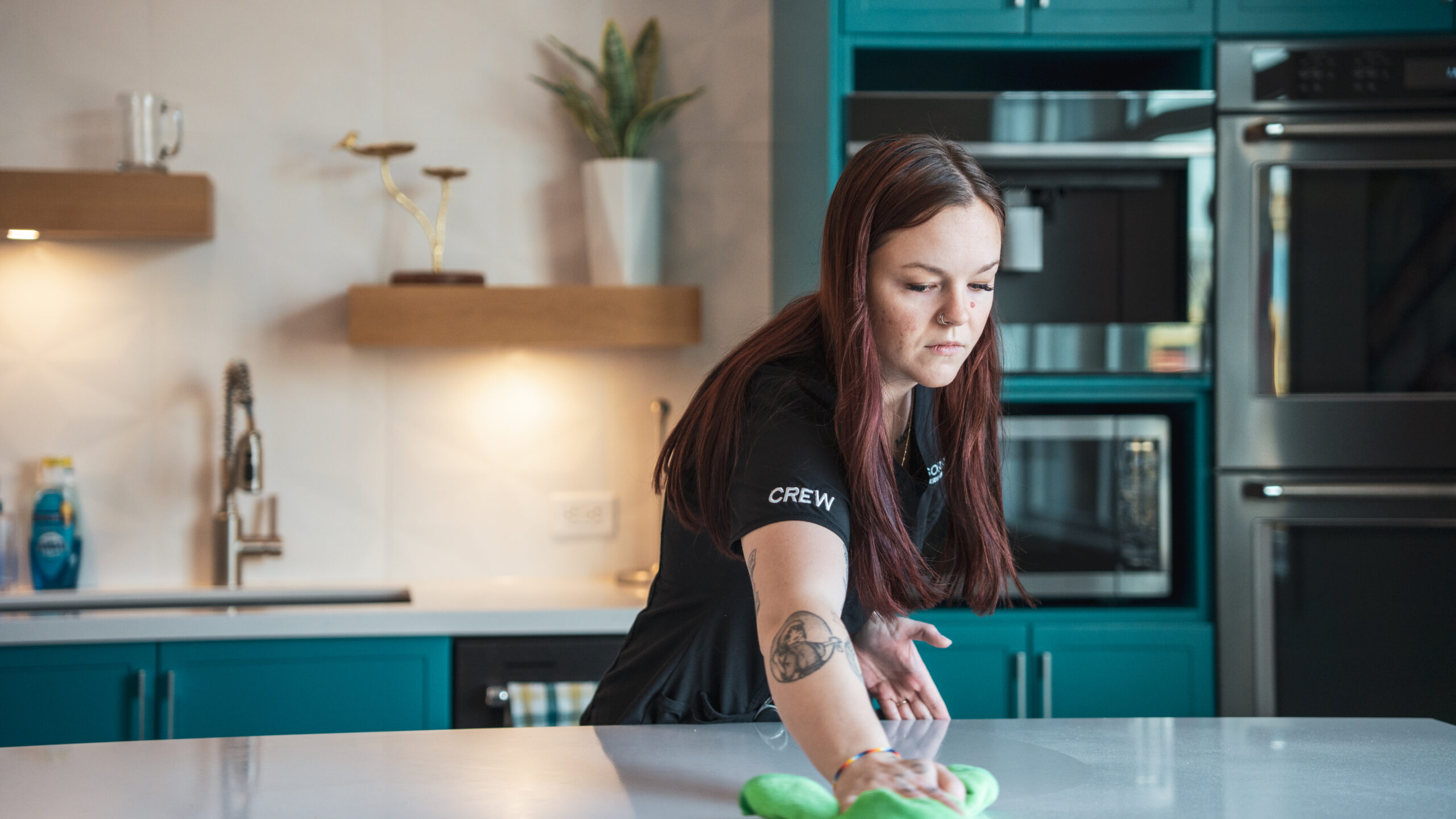Good Sorts crew member wiping down countertop with green rag in kitchen