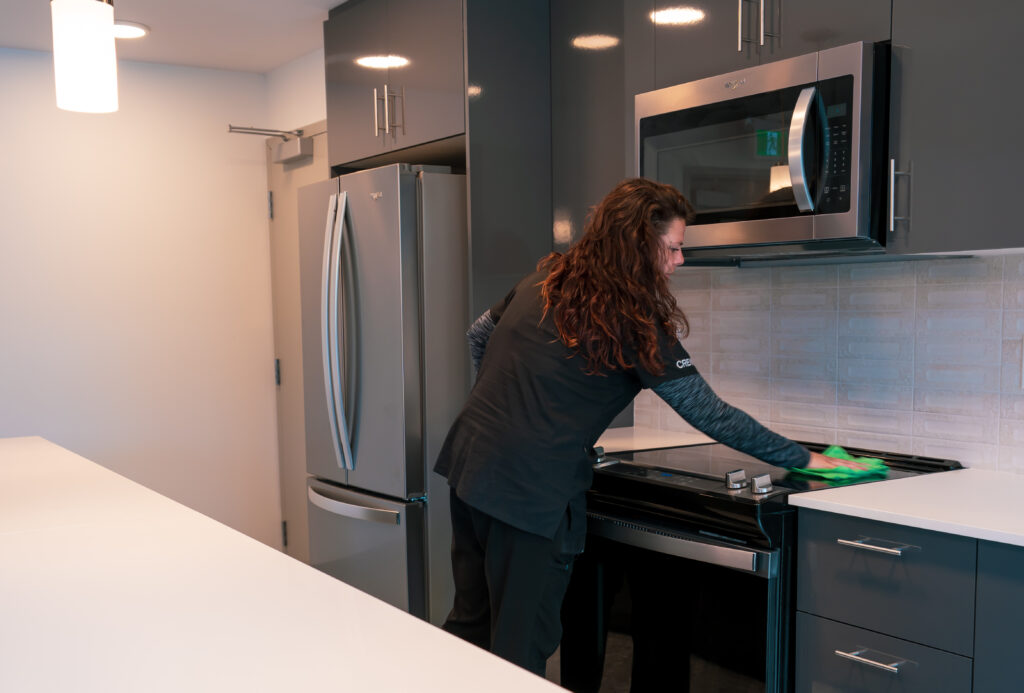 Good Sorts cleaning crew member wiping down shared kitchen space in amenity building