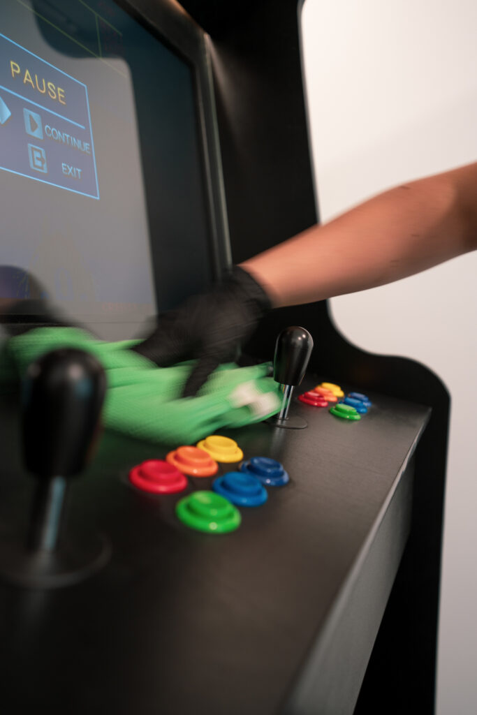 Good Sorts crew member wiping down arcade game in amenity building