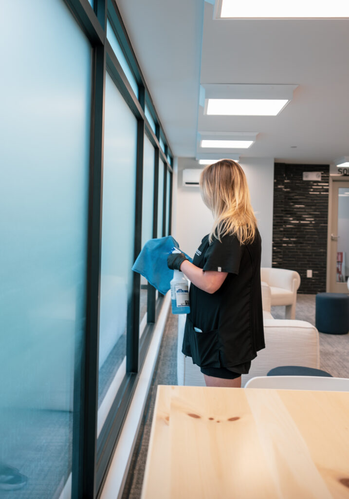 Good Sorts clean wiping down interior window of a Kelowna office
