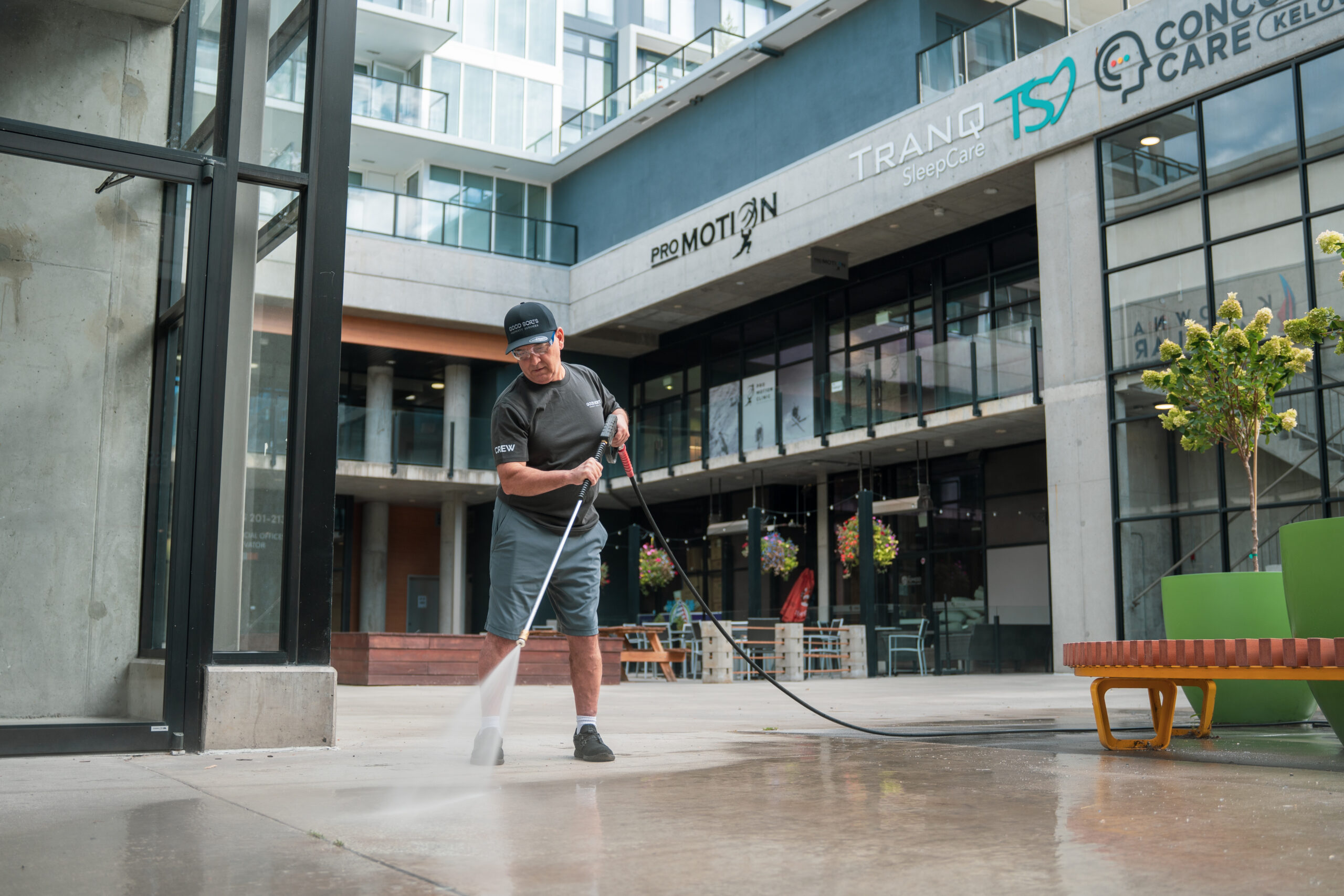 Good Sorts crew member pressure washing concrete courtyard in Kelowna